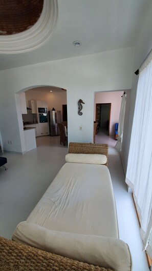 Un dormitorio amplio con una cama grande, una kitchenette y un baño visible a través de un arco.