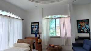 A modern living room with a circular brick ceiling, a sofa, a blue armchair, a wicker ottoman, and a bed. - Spacious modern apartment Golden Zone 2F (Bucerias)