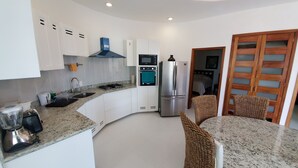 A modern kitchen with white cabinets, a built-in oven, a refrigerator, and a granite countertop. - Spacious modern apartment Golden Zone 2F (Bucerias)
