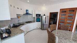 A modern kitchen with white cabinets, a built-in oven, a refrigerator, and a granite countertop.