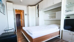 A bedroom with a wooden bed, white cabinets, and a television. - House by the sea 139a, Germany (Sylt)