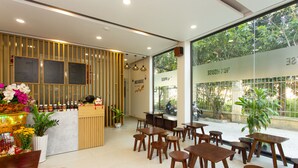 Un ristorante con tavoli e sedie in legno, un bancone con il menu, e vista all'esterno tramite ampie finestre.