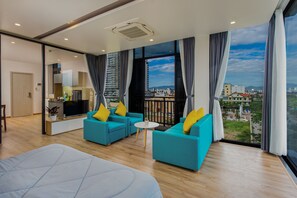 A modern hotel room with a balcony, large windows, and a view of the city.