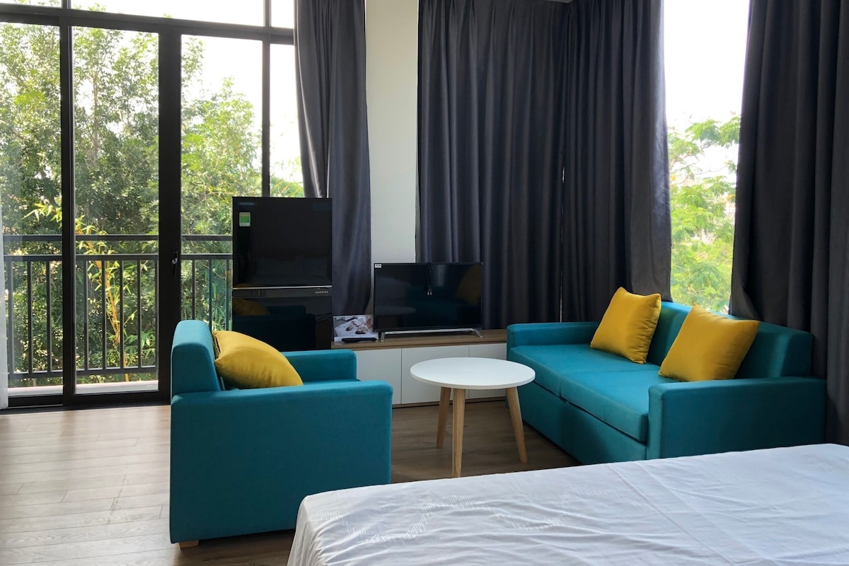 A modern hotel room with a balcony, a sofa set, a TV, and a bed.