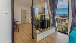 Un soggiorno moderno con una grande finestra, una TV a schermo piatto, un pavimento in legno e vista sulla città.