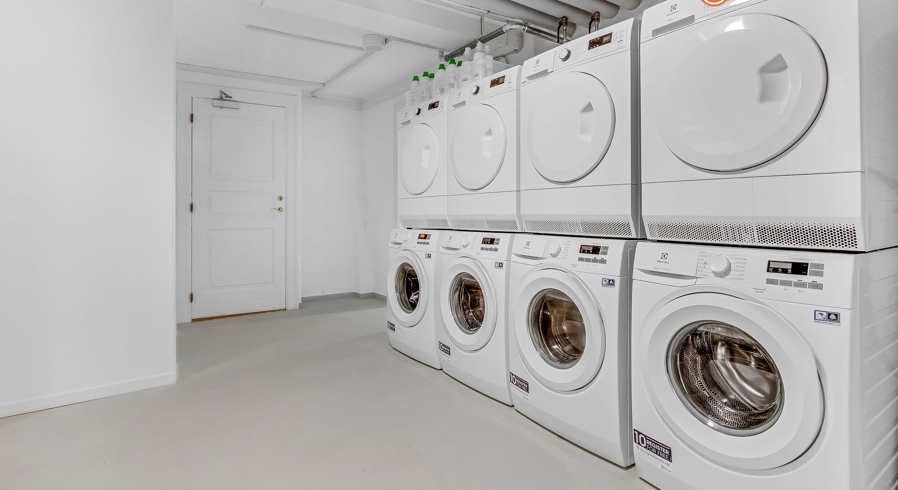 A laundry facility with multiple rows of stacked washing machines.