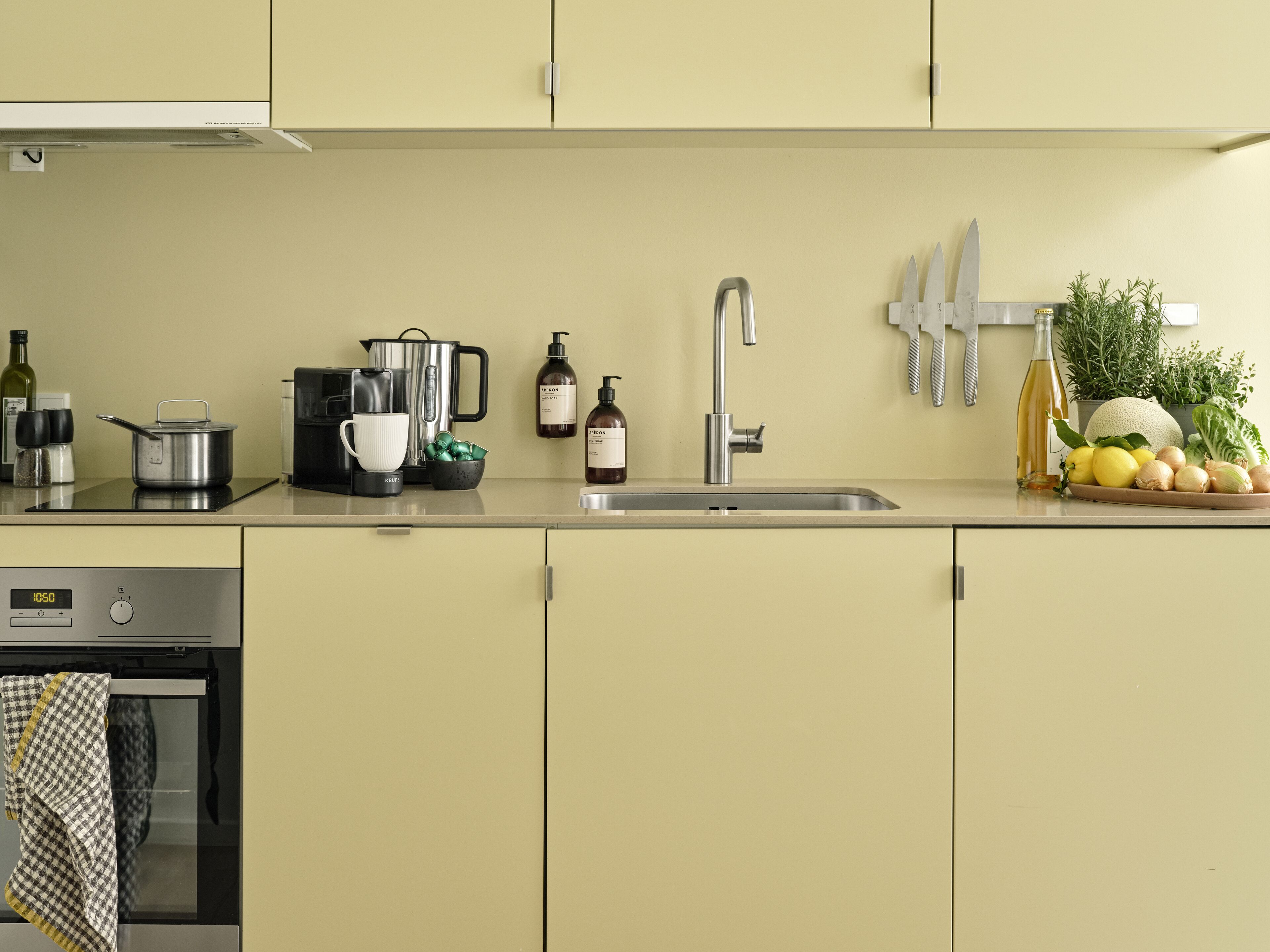 A kitchen with a stove, coffee maker, kettle, sink, and various kitchen items.