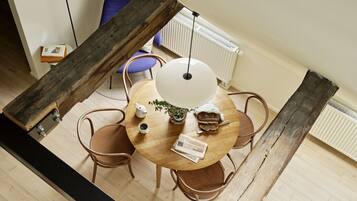 A dining area with a round wooden table, four chairs, a white table lamp, and a radiator in the background.