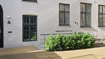 A building with multiple windows, a bench, and a small garden area.