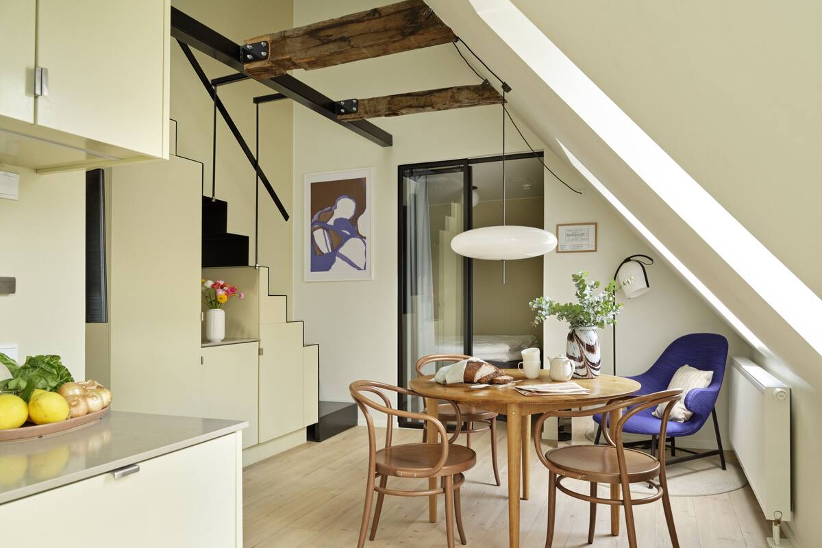 Une cuisine moderne avec un coin repas, des chaises en bois, une table et une chaise bleue.