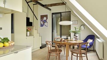 A modern kitchen with a dining area, wooden chairs, a table, and a blue chair.