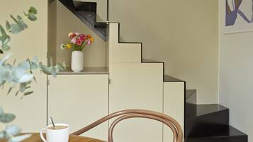A modern kitchen with a white cabinet, a black staircase, and a white vase with flowers on the counter.