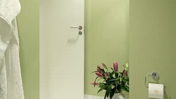 Ein Badezimmer mit grünen Wänden, einer weißen Tür, einer weißen Toilette, einem weißen Waschbecken und einem weißen Handtuchhalter.