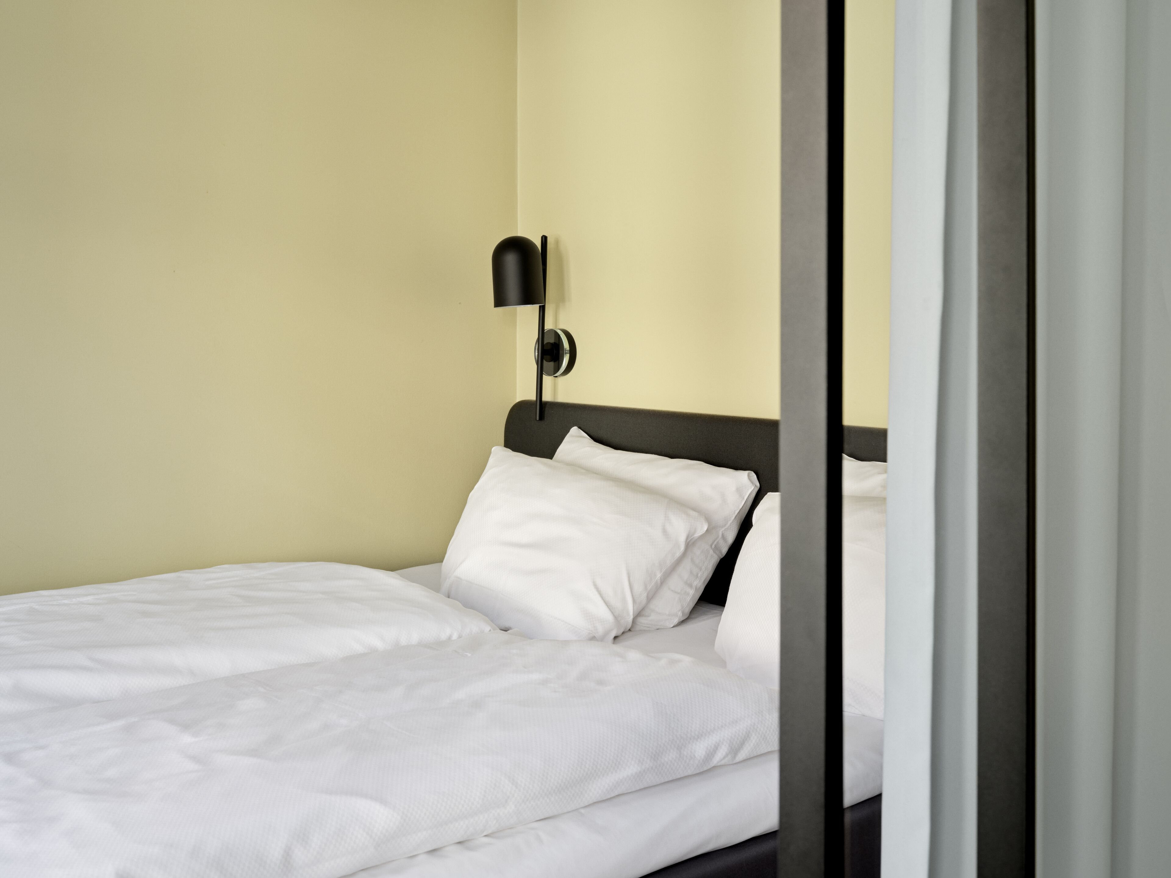 En pænt redt seng med hvide sengetæpper i et hotelværelse.