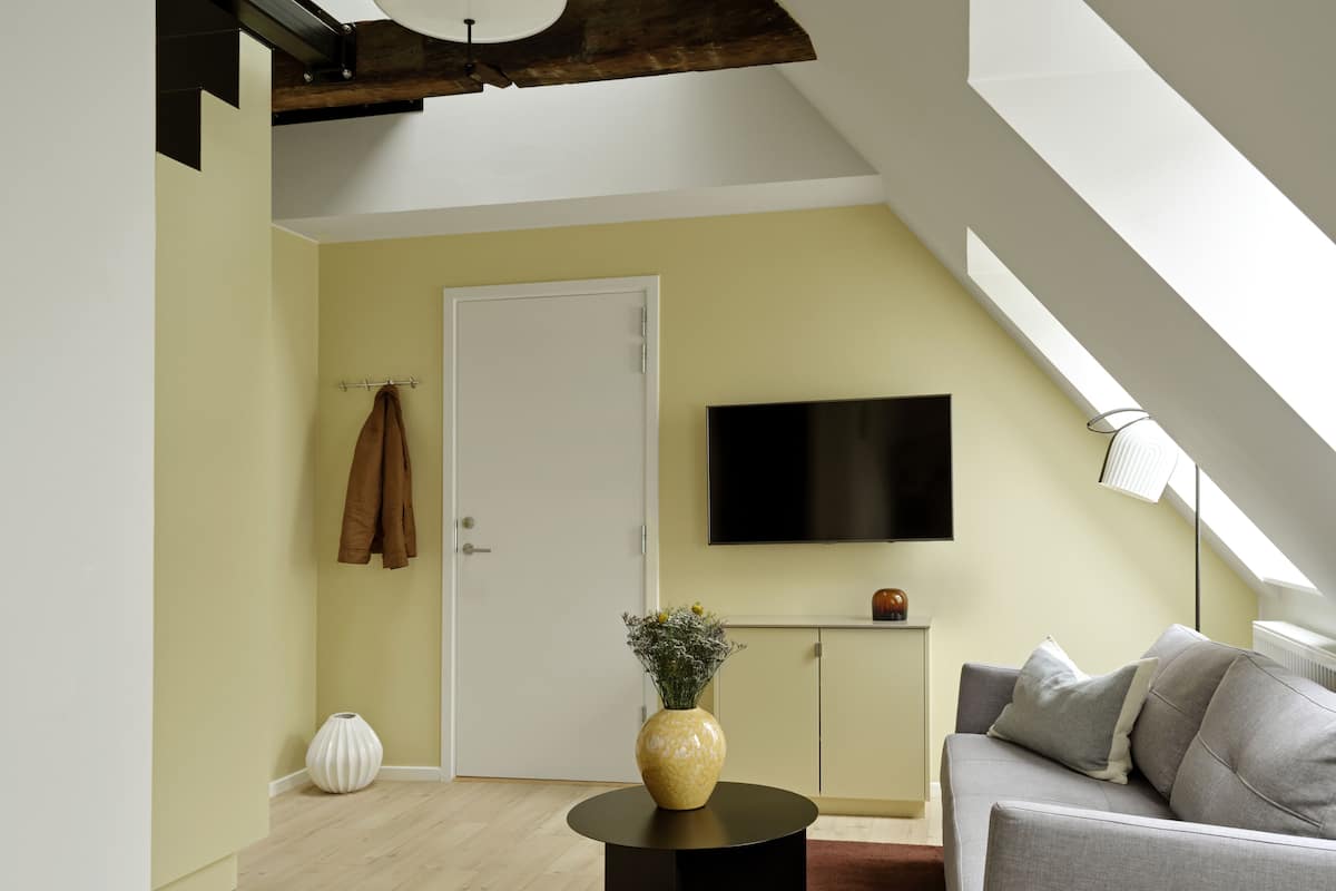 Un salon moderne comprenant un canapé, une table basse, un téléviseur fixé au mur et une porte.
