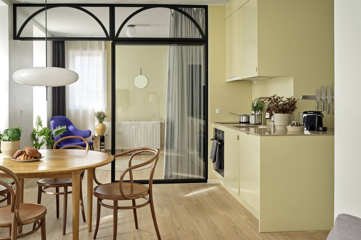 Une cuisine moderne avec un coin repas, des meubles en bois et une vue sur l’extérieur grâce à une porte vitrée.
