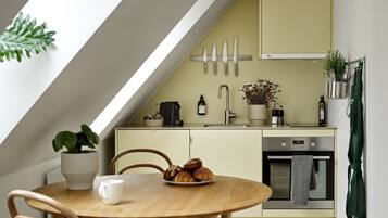 Una cocina moderna con un tragaluz, una mesa de comedor con sillas, una cafetera y una planta en maceta.