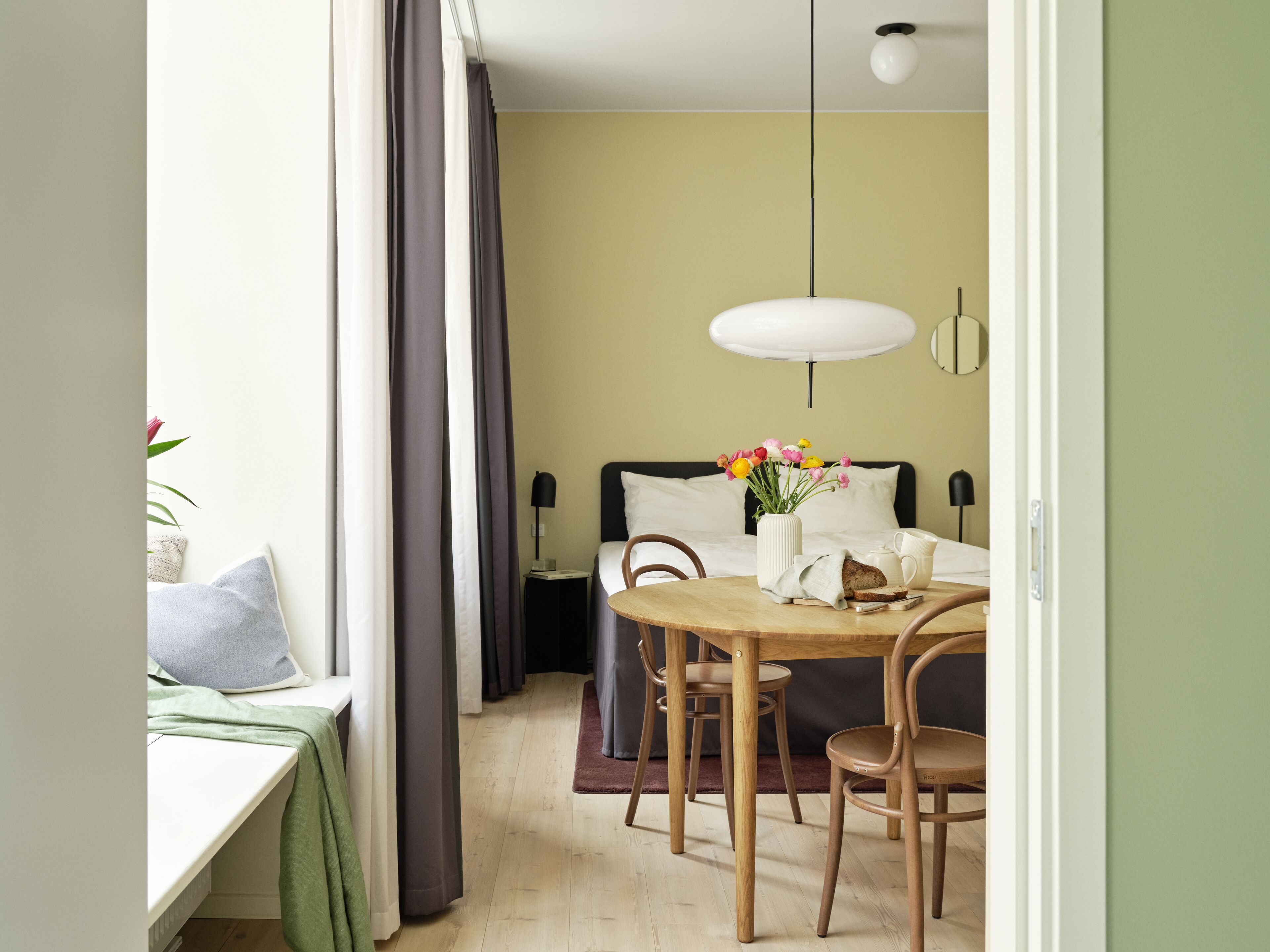 Ett hotellrum med en säng, ett nattduksbord och en matplats med ett bord och stolar.