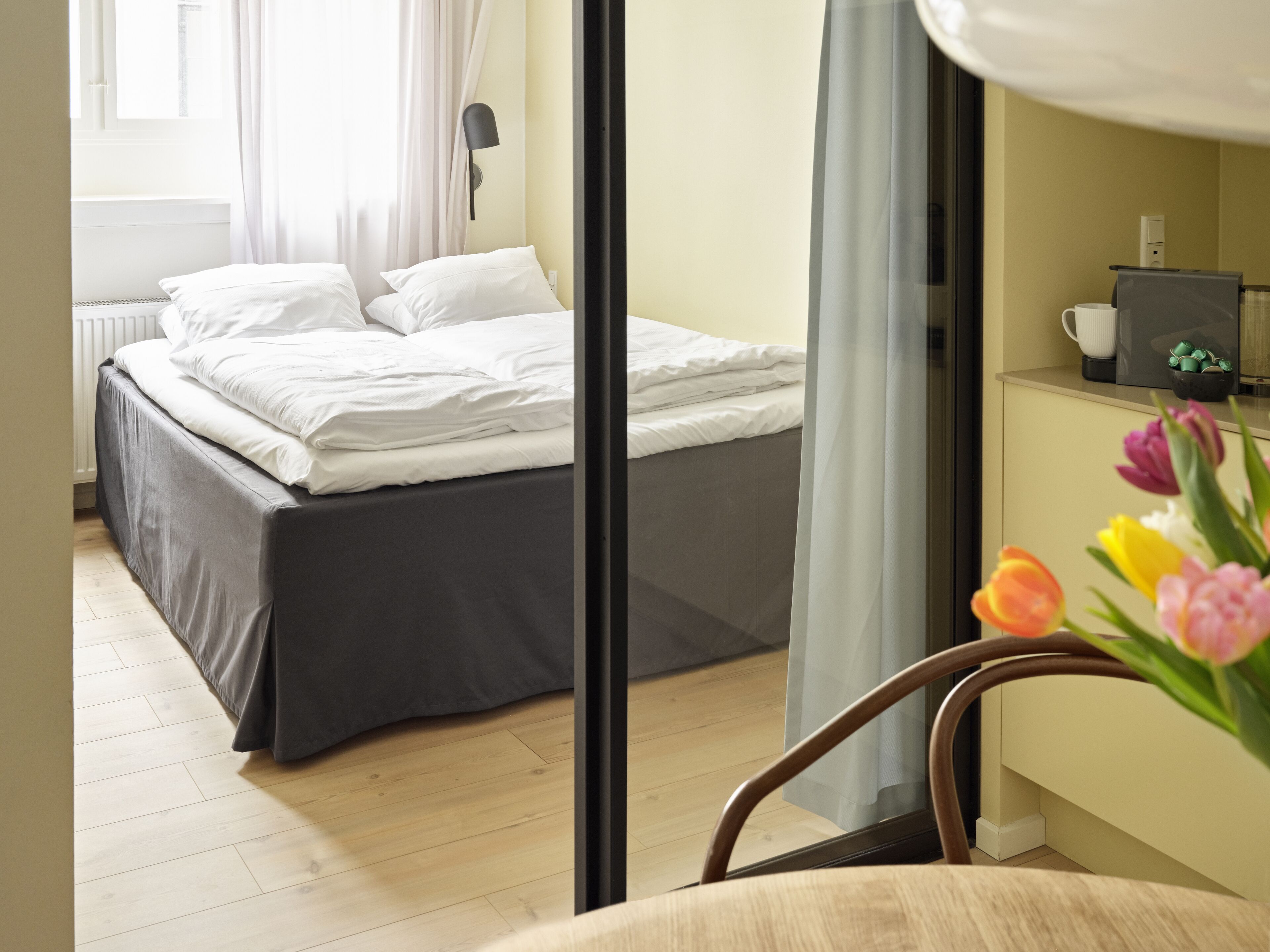 Habitación de hotel con cama, escritorio, silla y ventana con cortinas.