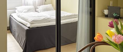 Habitación de hotel con cama, escritorio, silla y ventana con cortinas.