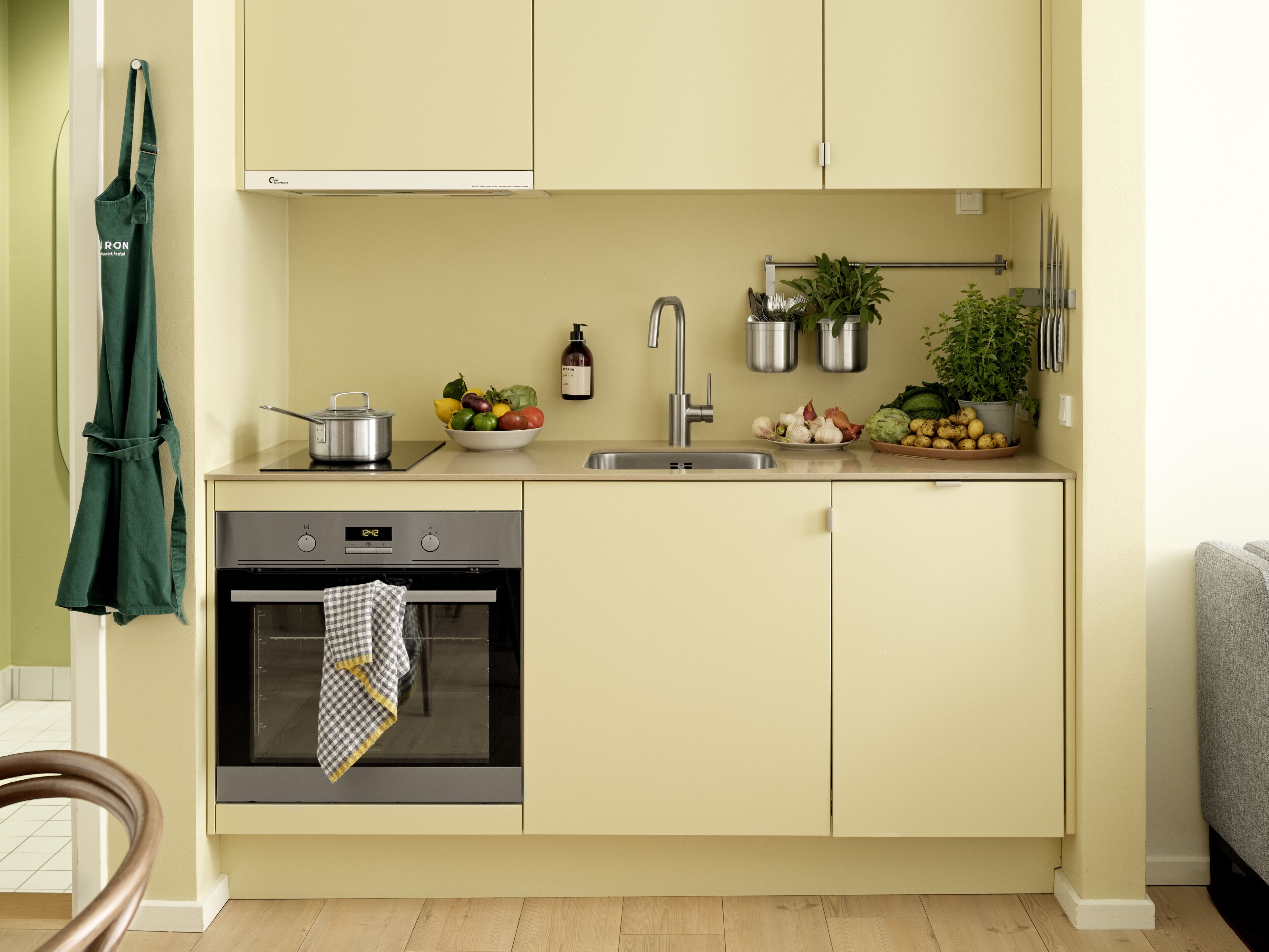 A compact kitchen with a stove, oven, sink, and a small countertop with various kitchen items.