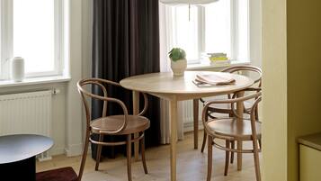 Un comedor con una mesa redonda de madera, cuatro sillas, una planta en maceta y una lámpara colgante.