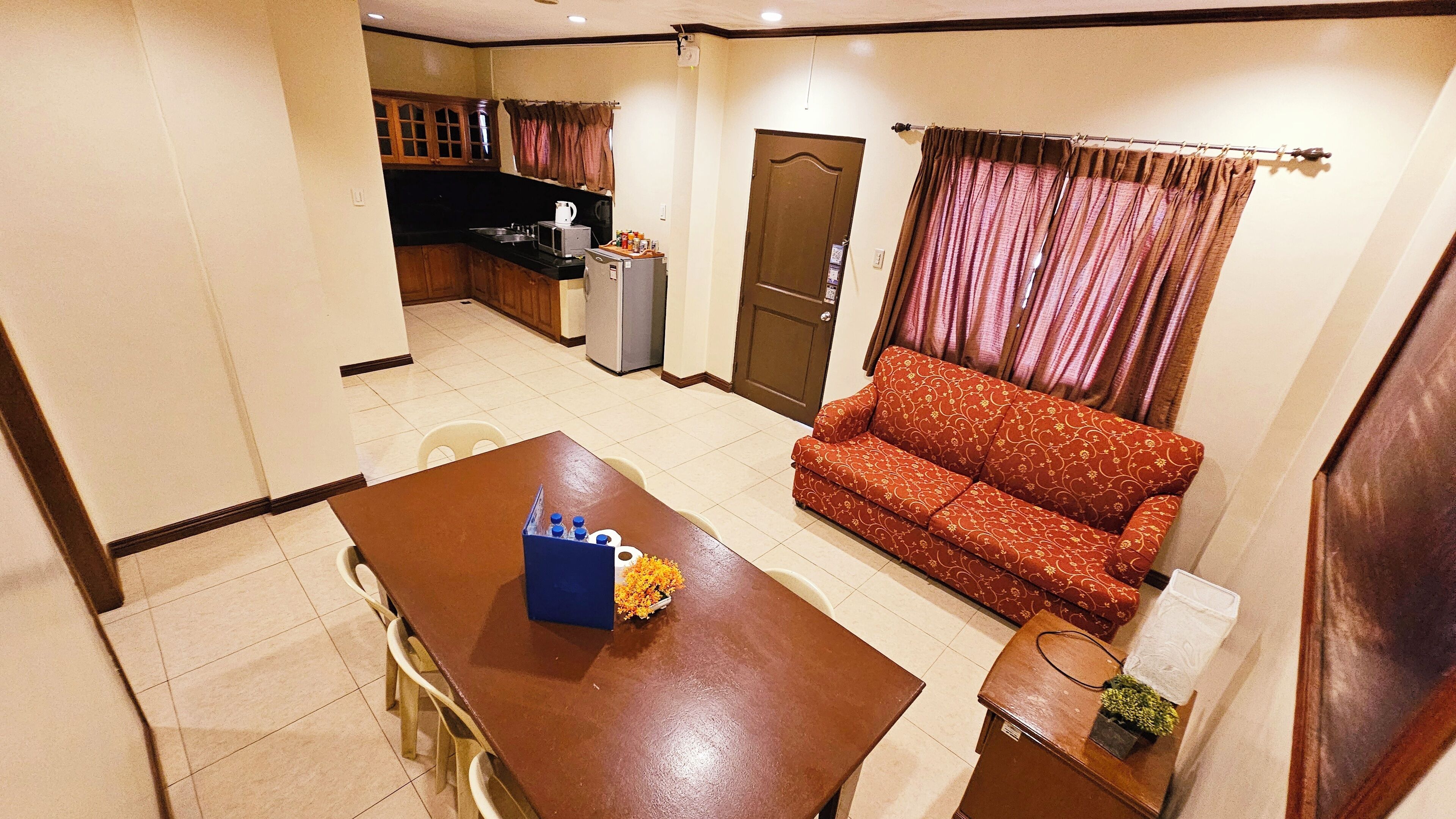 A compact living space with a dining table, a sofa, a kitchenette, and a door.