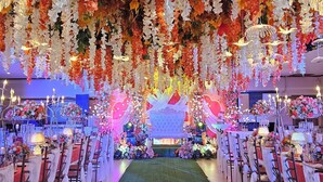 Une salle de banquet avec des rangées de tables, des chaises et une scène centrale.