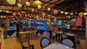 Un restaurant intérieur avec des tables et des chaises, un comptoir et des lanternes en papier suspendues.