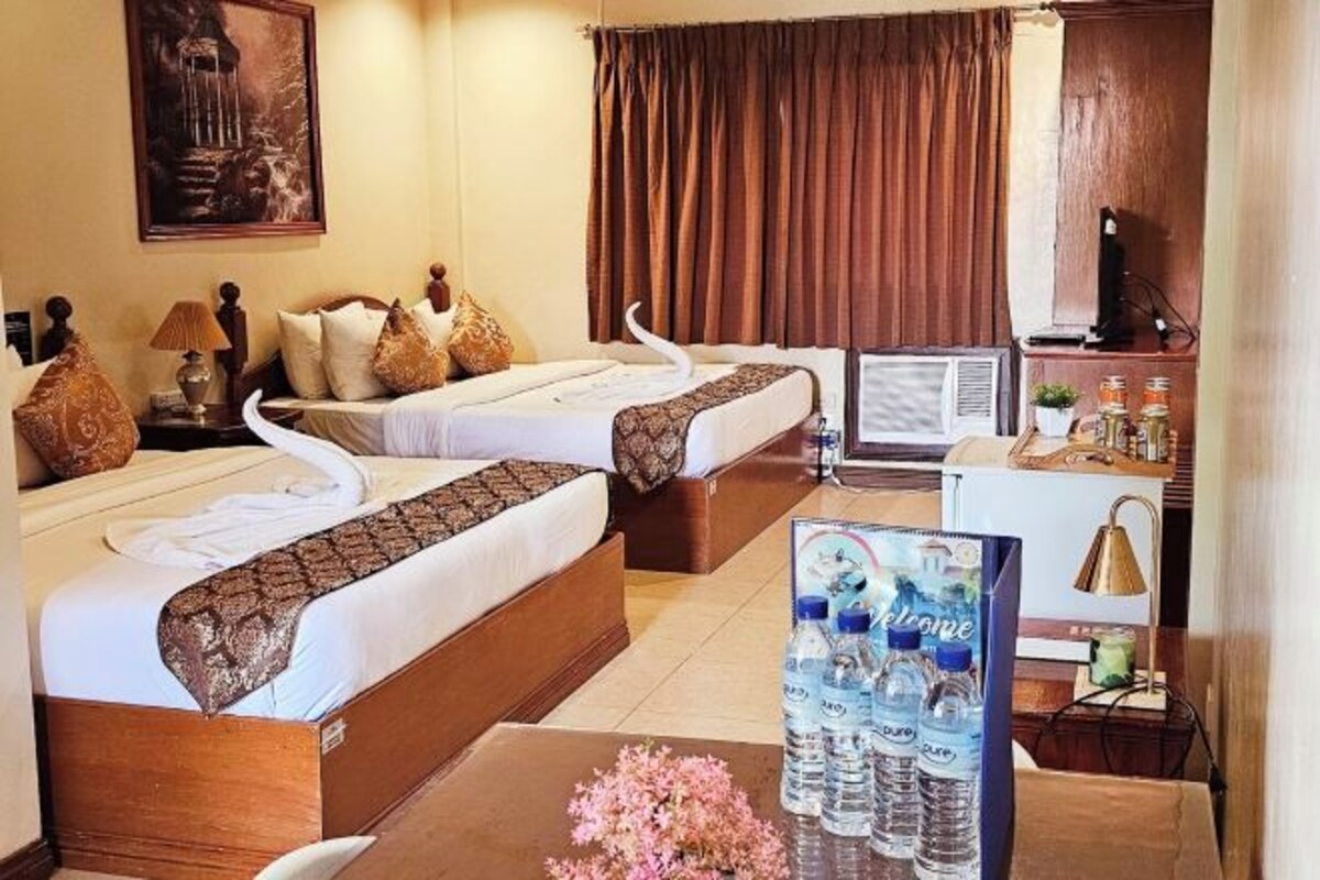 A hotel room with two beds, a desk, a television, and a minibar.