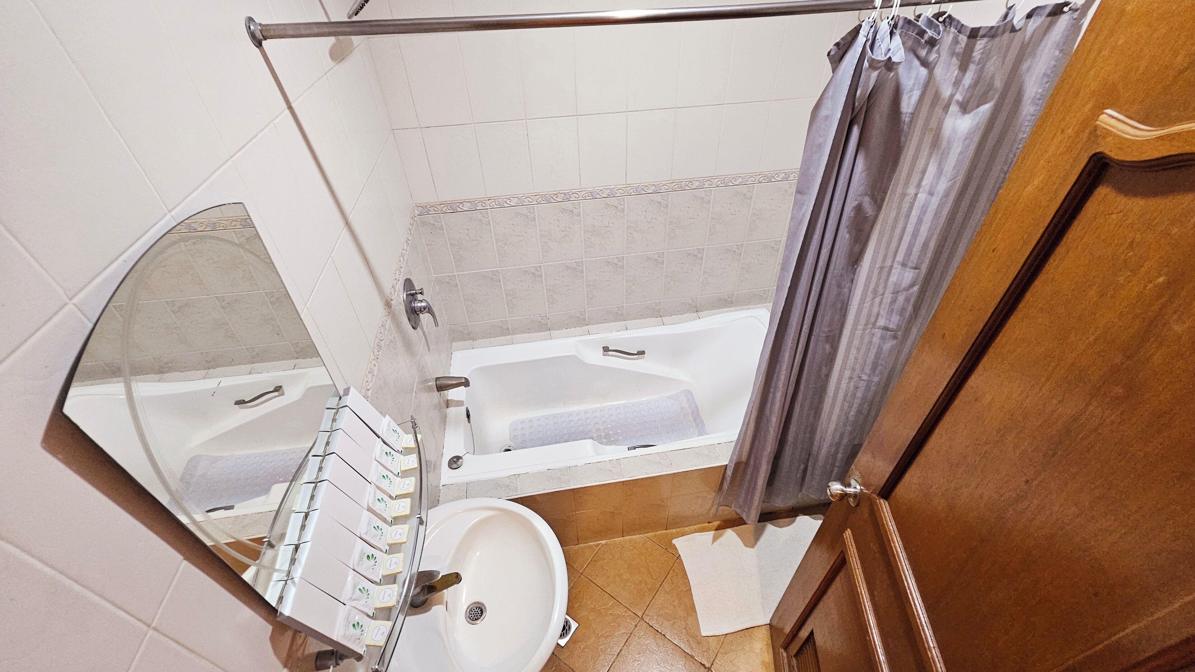 A bathroom with a bathtub, a sink, and a shower curtain.