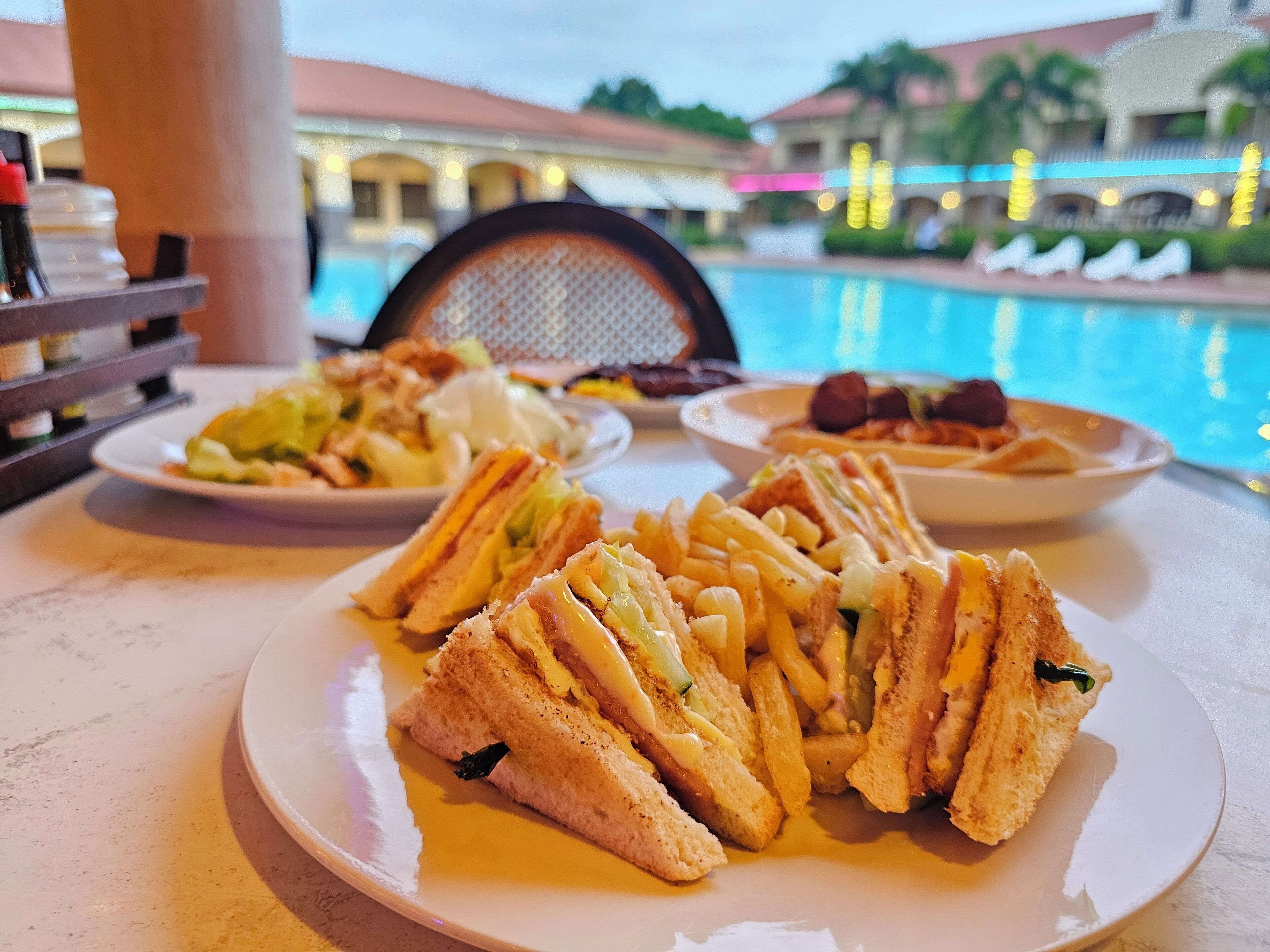 A poolside dining area with a table set for a meal.