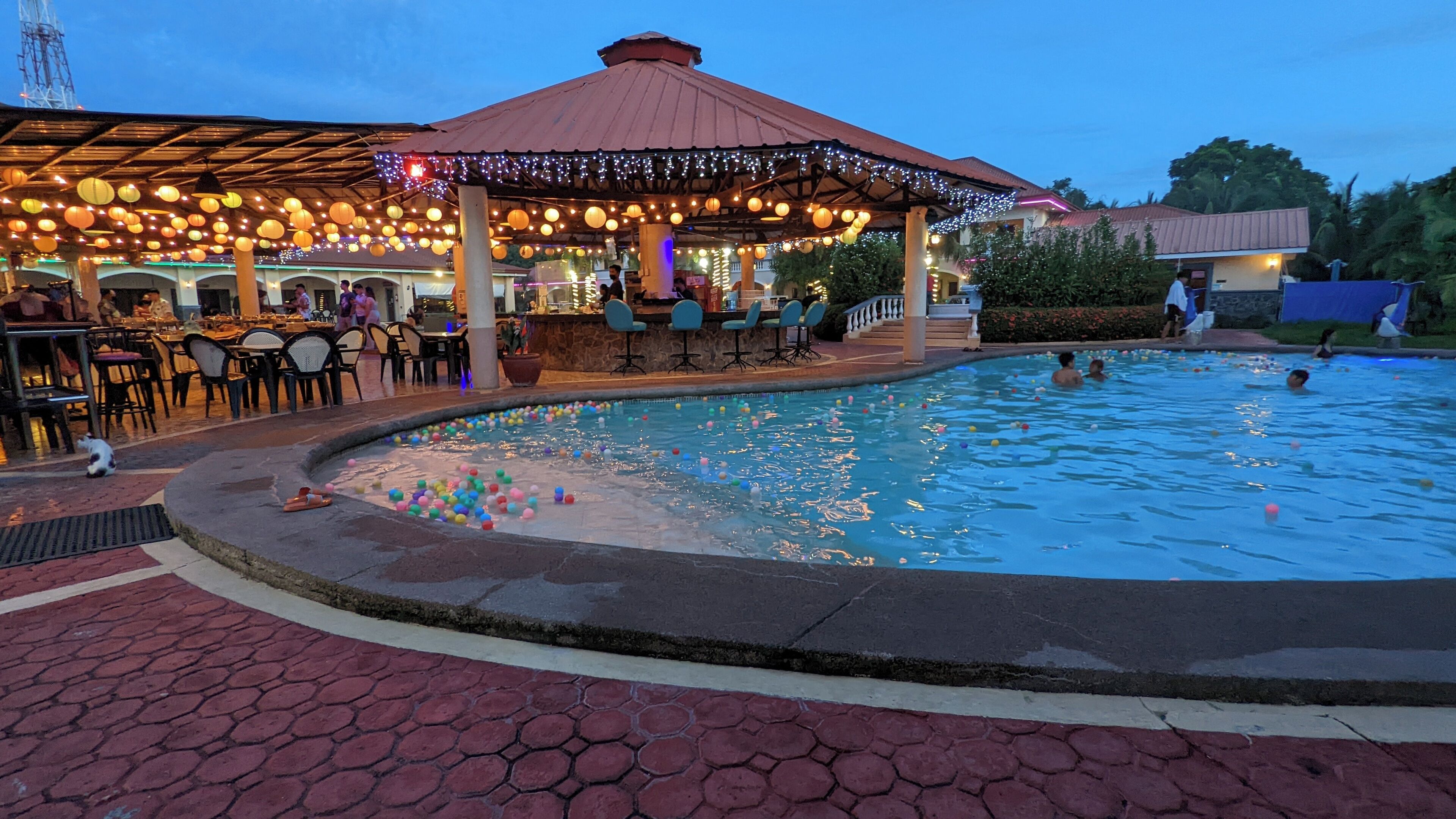 A pool area with a covered seating area and a bar.