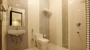 A bathroom with a sink, mirror, toilet, and shower. - Hotel Airport International (New Delhi)
