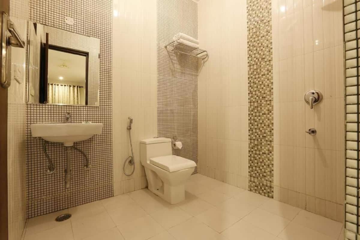 A bathroom with a sink, mirror, toilet, and shower.