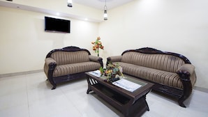 A living room with two sofas, a coffee table, and a flat-screen TV mounted on the wall. - Hotel Airport International (New Delhi)
