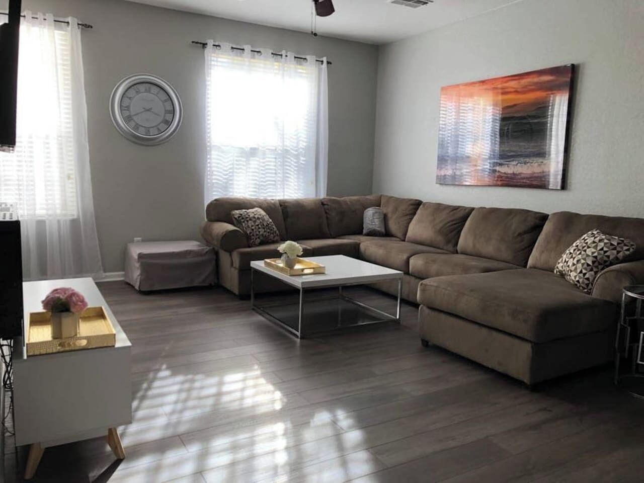 A modern living room with a sectional sofa, a coffee table, and a wall clock.