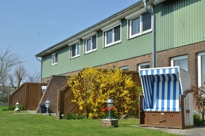 A two-story residential building with a green exterior, a brick facade, and a wooden fence.