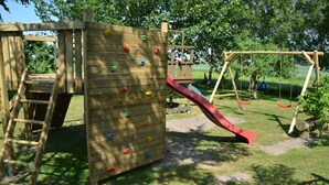 A wooden play structure with a climbing wall and a red slide. - Double room no. 3 - Ferienhof Feil (Friedrichskoog)