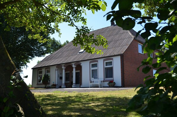 A two-story house with a brick exterior, a pitched roof, and a front porch with columns.