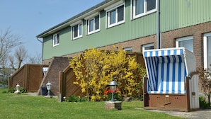 A two-story residential building with a green exterior, a brick facade, and a wooden fence. - Double room no. 3 - Ferienhof Feil (Friedrichskoog)