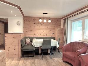 Un comedor con pared de madera, una mesa con mantel blanco y un sillón rojo.