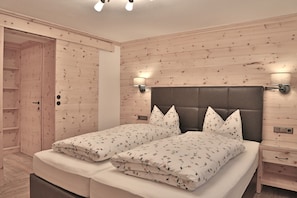 Un dormitorio con una cama doble, paredes de paneles de madera, dos mesitas de noche y un armario.