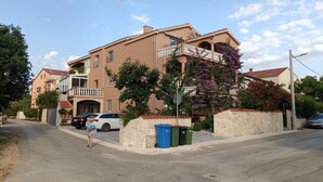 Un edificio residencial con balcón, entrada para vehículos y calle.
