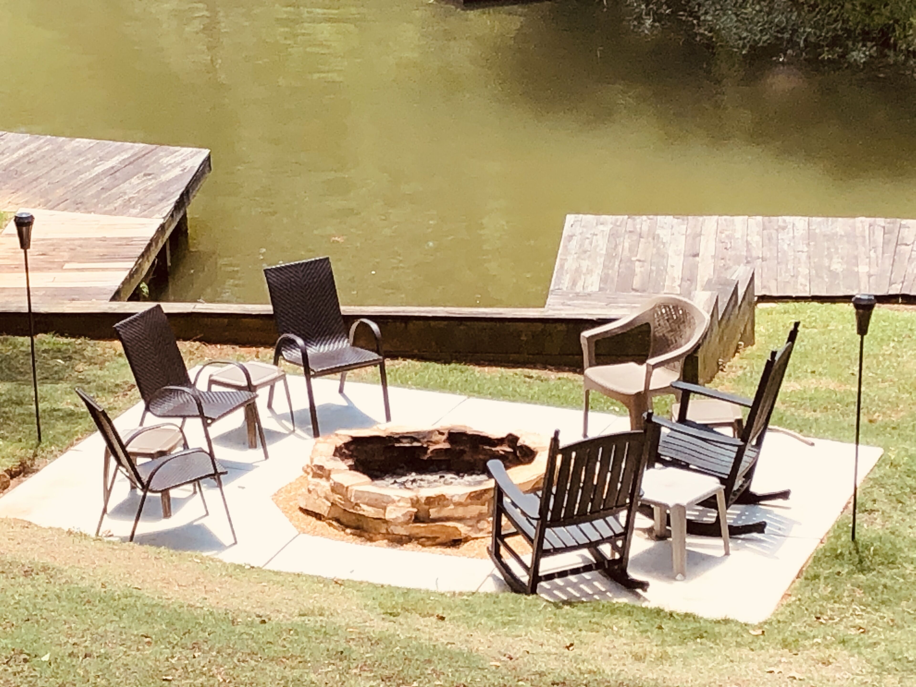An outdoor seating area with a fire pit, chairs, and a view of a water body.