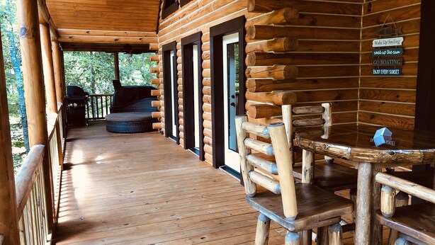 Una baita di legno con veranda, un tavolo e delle sedie.