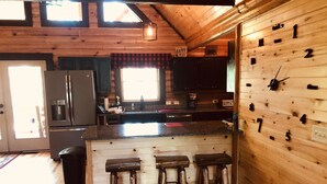 Una cucina con pareti in legno, un frigorifero, un lavello e una sveglia.