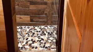 Un angolo doccia con pareti in legno e pavimento piastrellato.