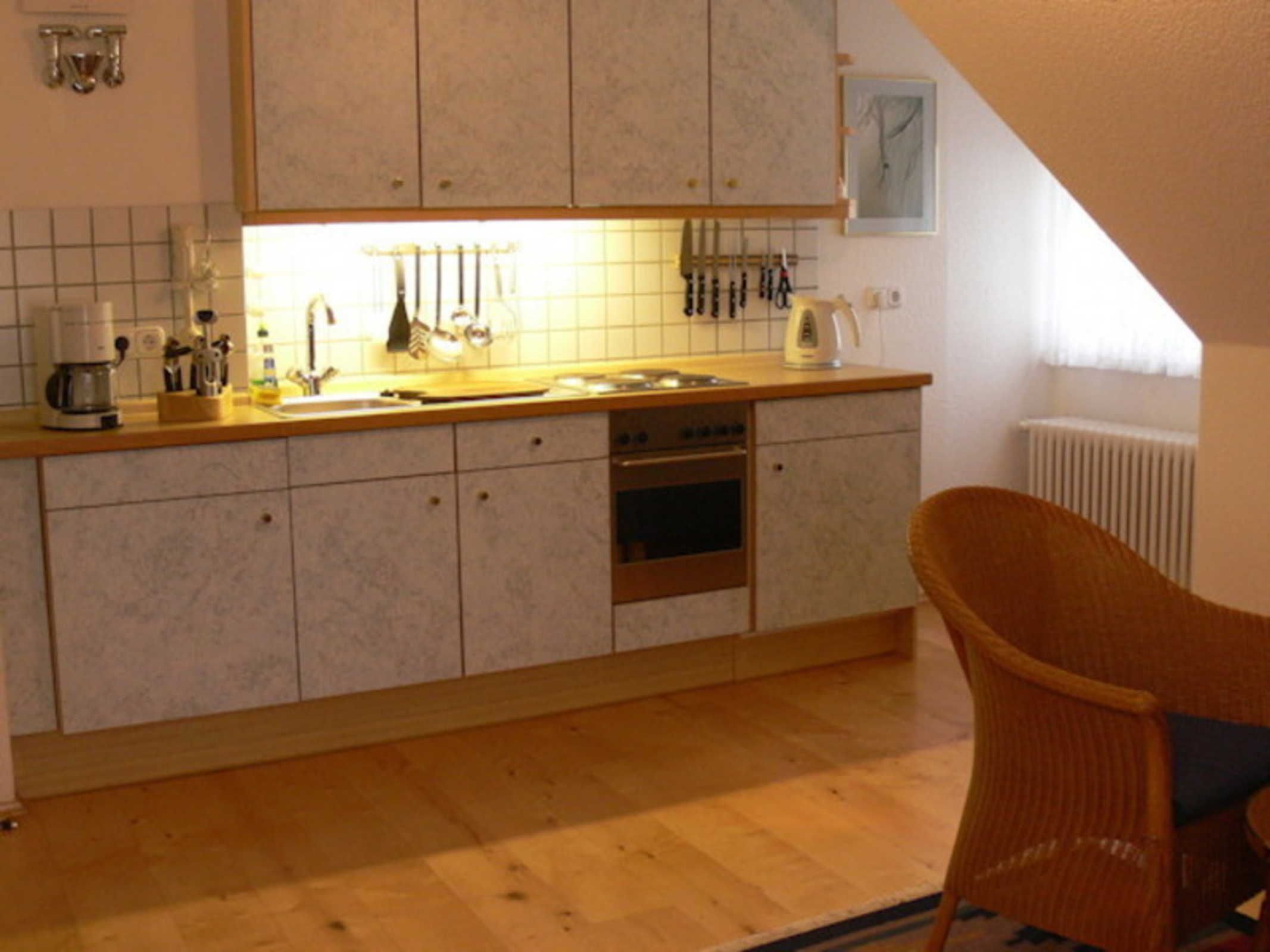 Une cuisine avec un plan de travail en bois, un four encastré et une chaise.