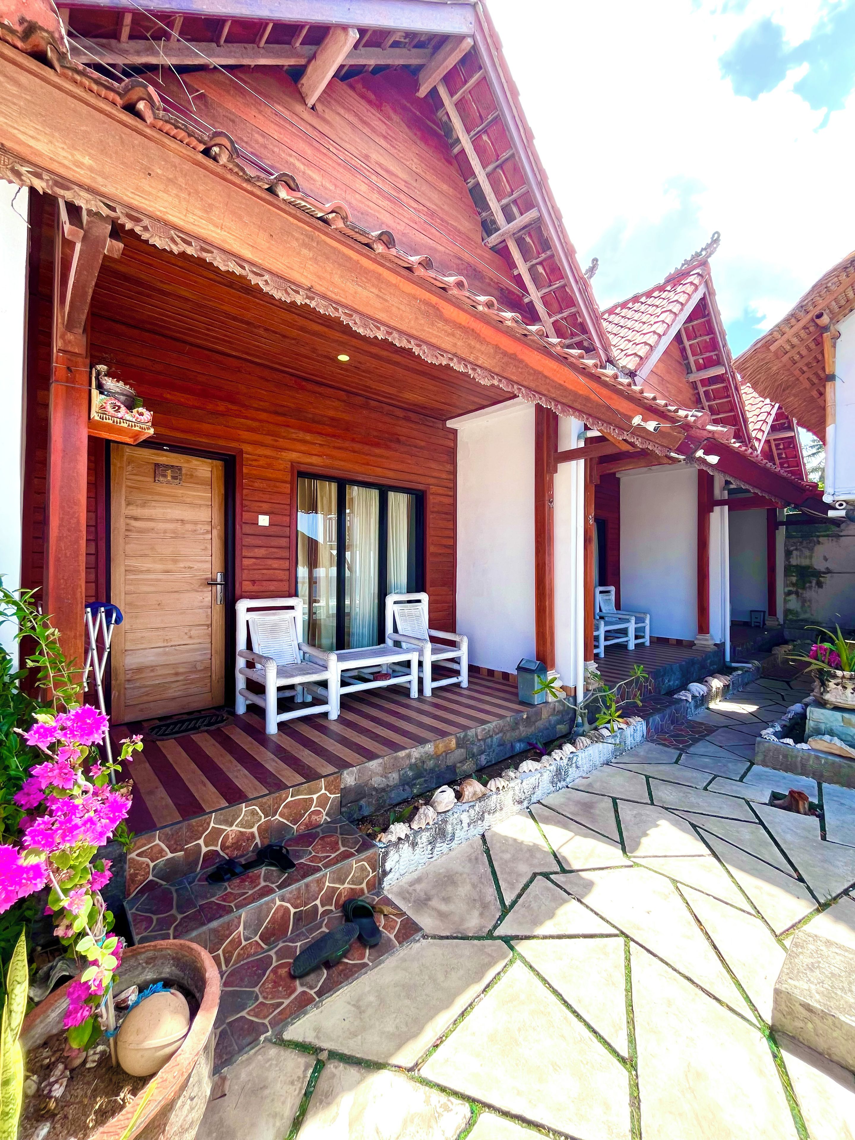 A wooden building with a porch, a door, and a seating area with chairs.